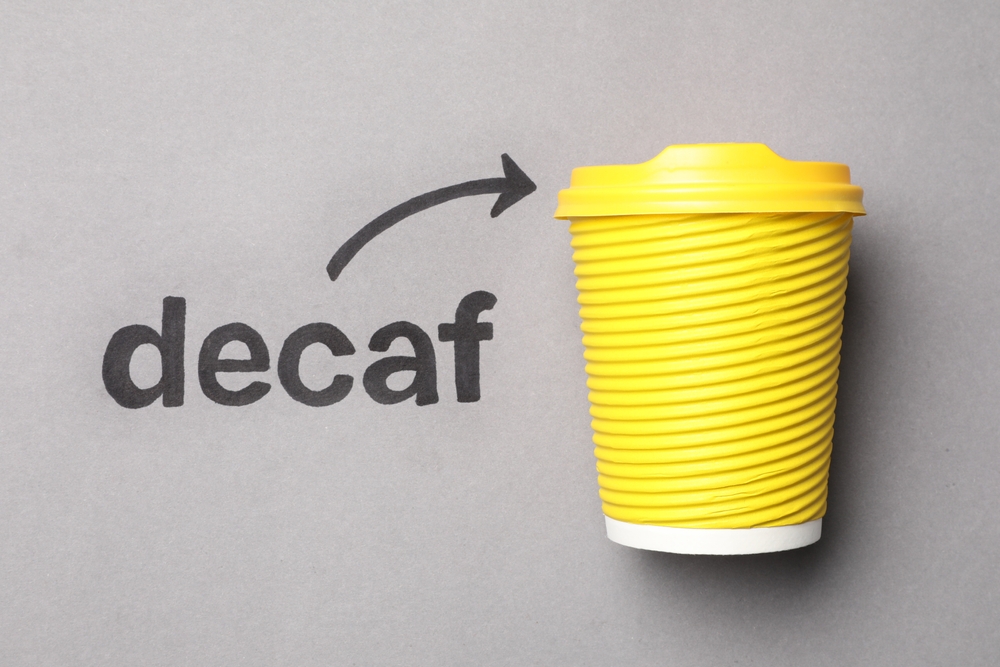 A yellow cup with decaf coffee to illustrate who made decaf coffee first.